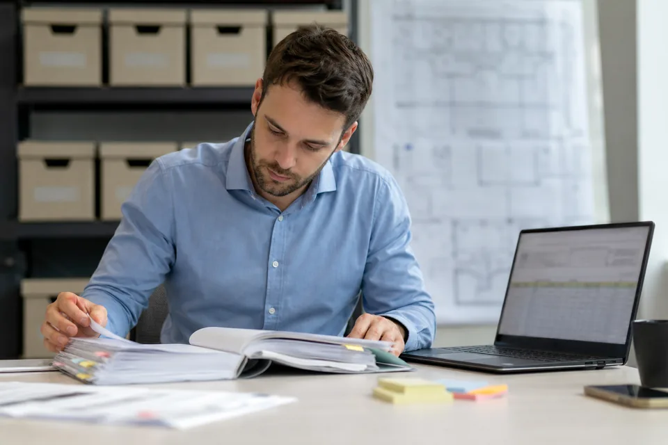 Lease administrator checking a scanned commercial lease against a spreadsheet of lease fields